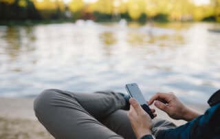 kaboompics Young Man Using His Phone on beach 1